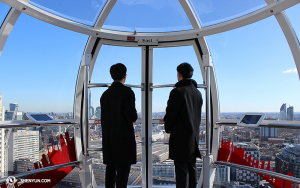 Sementara itu, di London, anggota orkestra Shen Yun International Company mengunjungi London Eye. Peniup Trombon Tianli Hong (kiri) dan pemain biola Joshua Lin sedang memandang ke arah timur. (Foto oleh Darrell Wang)
