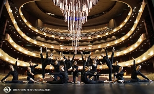 Pose Shen Yun World Company di Winspear Opera House di Dallas, Texas. Teater ini dirancang berdasarkan rumah opera tradisional abad ke-21. Lampu gantung besar teater tergantung di latar belakang.