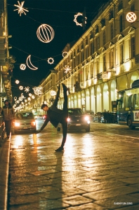Seorang penari menampilkan siluet anggun di bawah cahaya magis Luci d'Artista, sebuah instalasi seni terbuka di Turin, Italia.